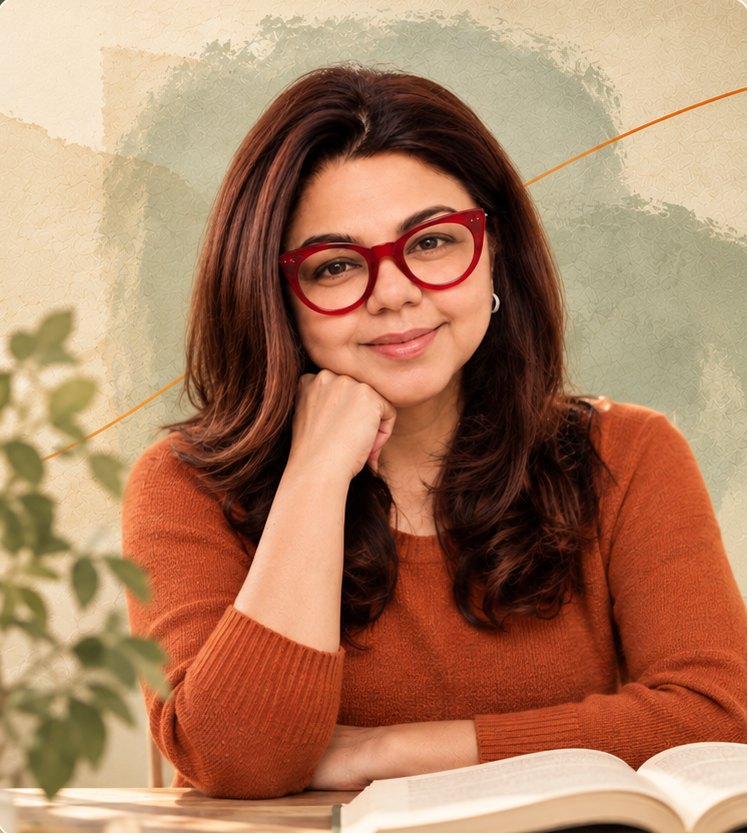 Sumona Singhal, smiling, seated at a desk with an open book